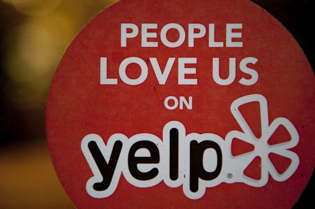 The Yelp Inc. logo is displayed in the window of a restaurant in New York